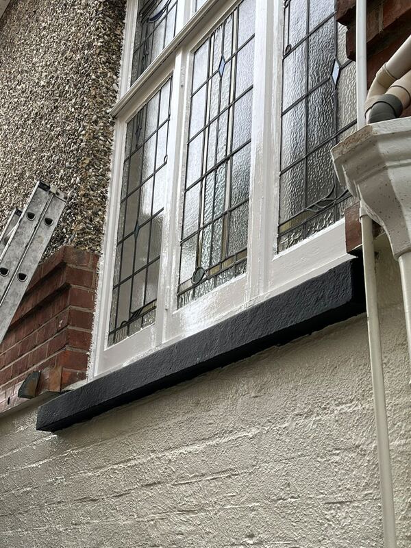 The same windows after painting, with white frames and a black sill